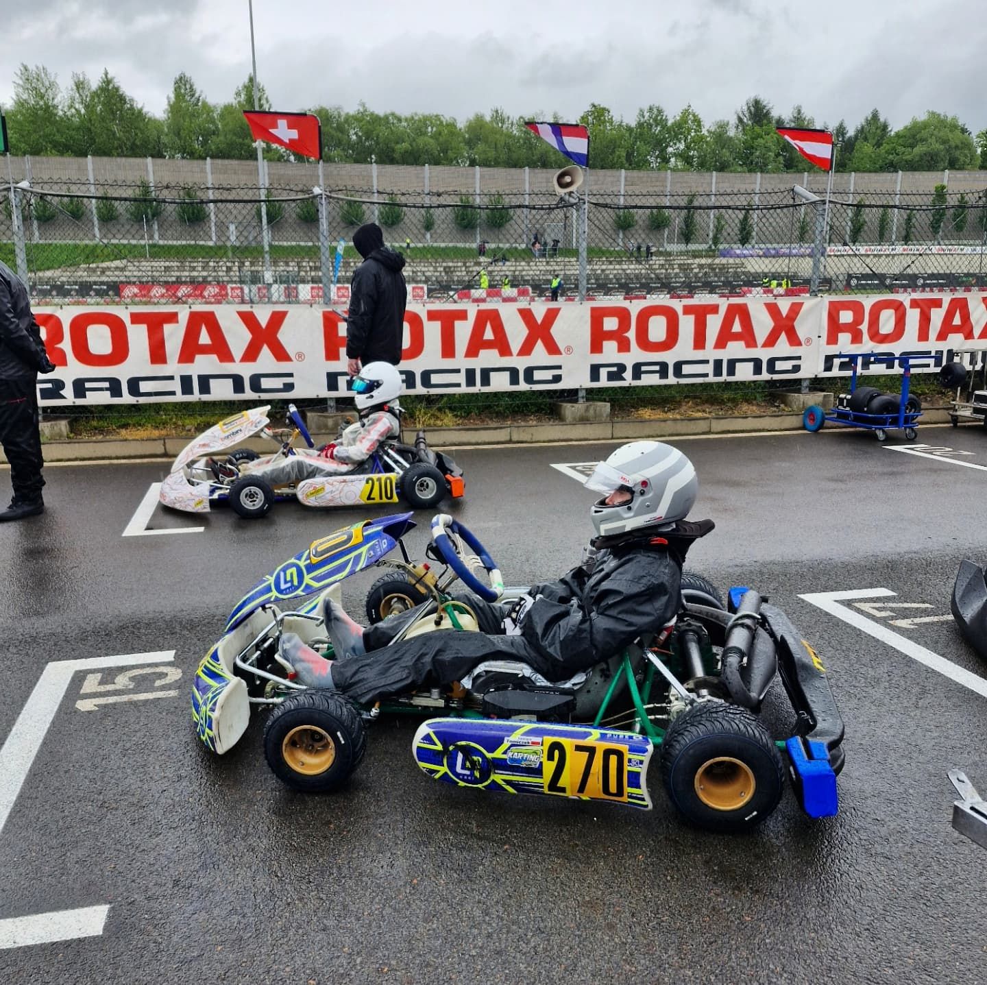 Gokart z numerem 270 na mokrym torze, w tle banery Rotax